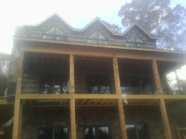 Dormers and porch framing on a large log home under construction — Roof Coating work by our crew in Calverton