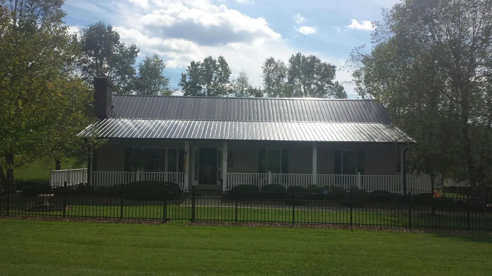 Gray metal roof on a brick ranch with a full width front porch — Gutter Guard Installation work by our crew in Calverton