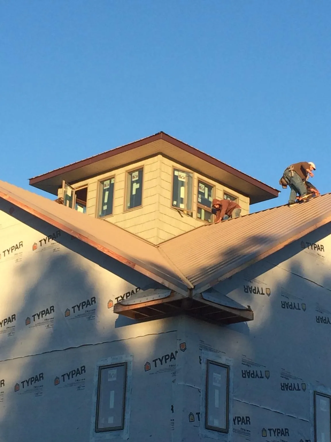 Roofers working around a rooftop cupola on a new metal roof at sunset — Roof Waterproofing in Calverton by Roofing Brothers